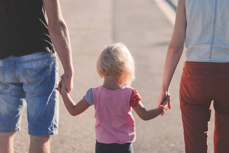 Eltern und Tochter gehen Hand in Hand